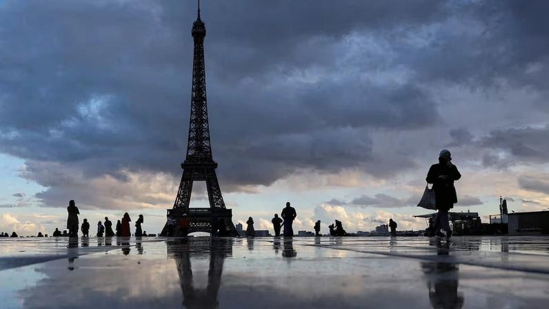 People stand at the Trocadero square near the Eiffel Tower in Paris