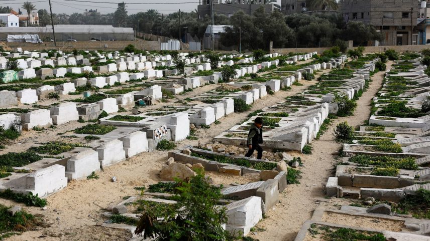 A Palestinian child walks through the cemetery with graves of some of those killed during the war, in Deir al-Balah, central Gaza Strip, January 30, 2026. REUTERS/Mahmoud Issa