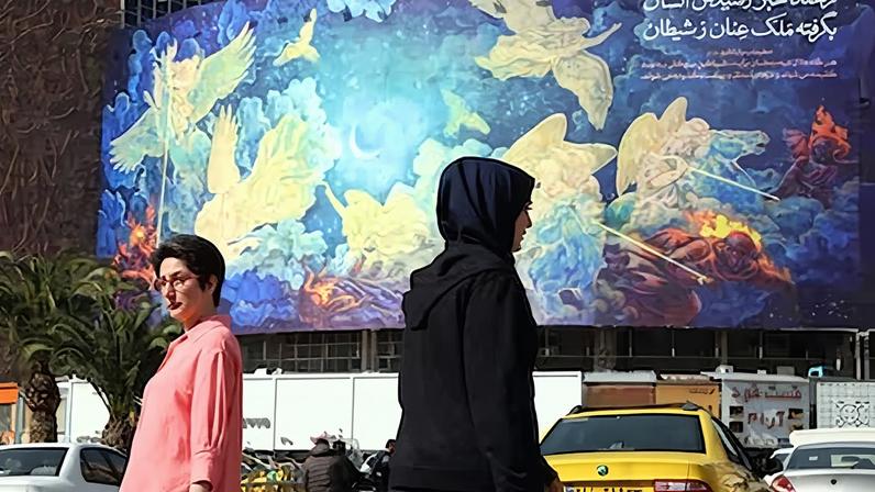 Iraníes pasan ante un cartel con la frase "El ser humano derrotará a los malvados", este sábado en la plaza Valiasr de Teherán.