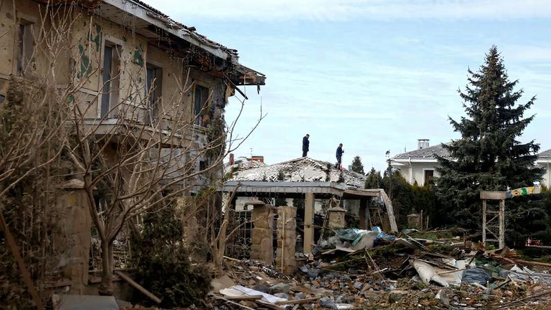 Men remove debris from the roof of a house at the site of residential area damaged by a Russian missile strike, amid Russia's attack on Ukraine, in Kyiv region, Ukraine February 22, 2026.