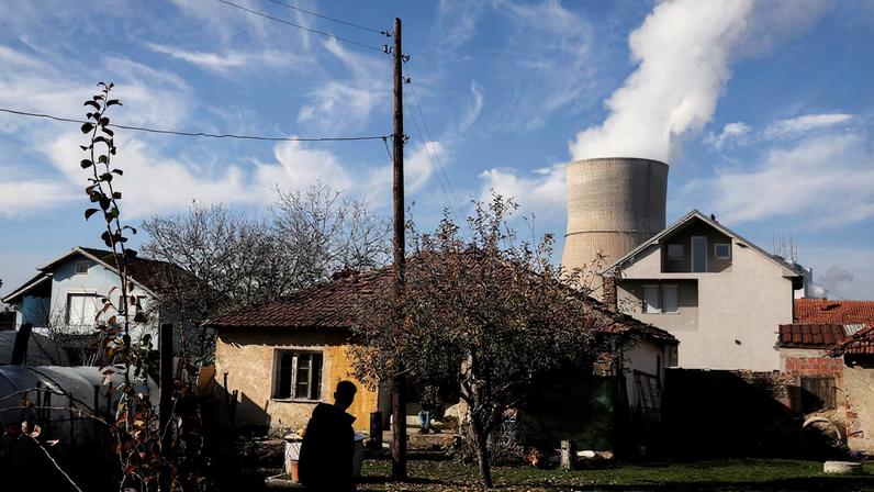 A man walks at his garden near the coal-fired power plant in Obilic