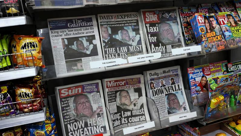 British newspapers, featuring coverage of the arrest of Andrew Mountbatten-Windsor, younger brother of Britain's King Charles, on suspicion of misconduct in public office, sit on display in a newsagent in London