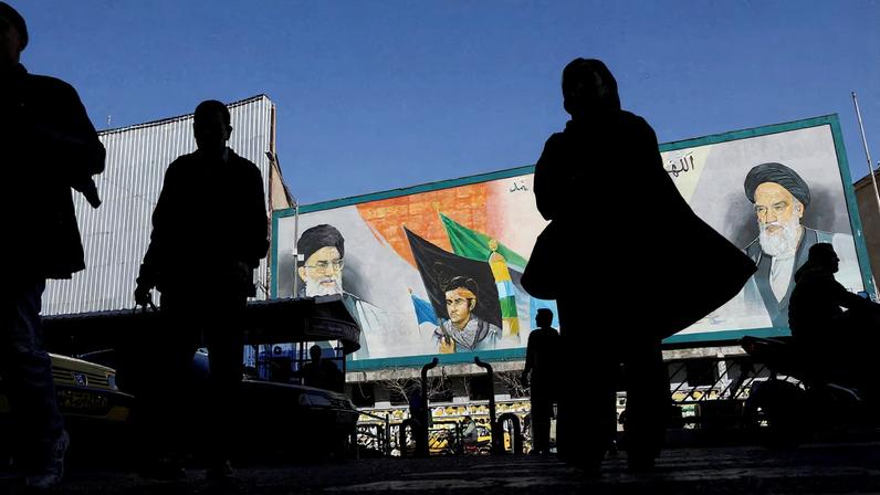 People walk near a mural featuring images of Iran's Supreme Leader Ayatollah Ali Khamenei and leader of Iran's 1979 Islamic Revolution Ayatollah Ruhollah Khomeini, on a street in Tehran, Iran, February 17, 2026.