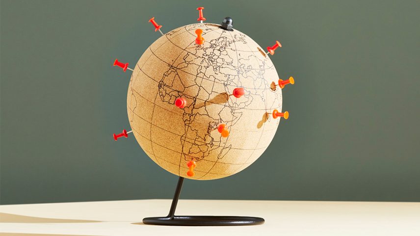 Imagem de um globo, em fundo cinza, com pins laranjas marcando alguns países.