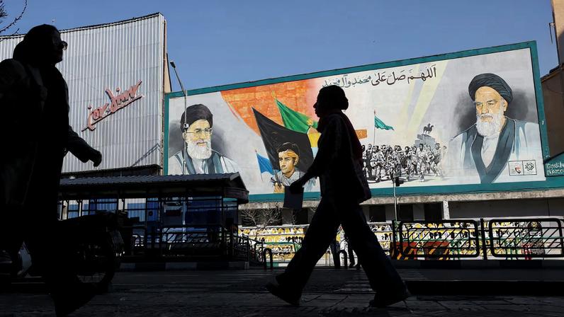 People walk near a mural featuring images of Iran's Supreme Leader Ayatollah Ali Khamenei and leader of Iran's 1979 Islamic Revolution Ayatollah Ruhollah Khomeini, in Tehran