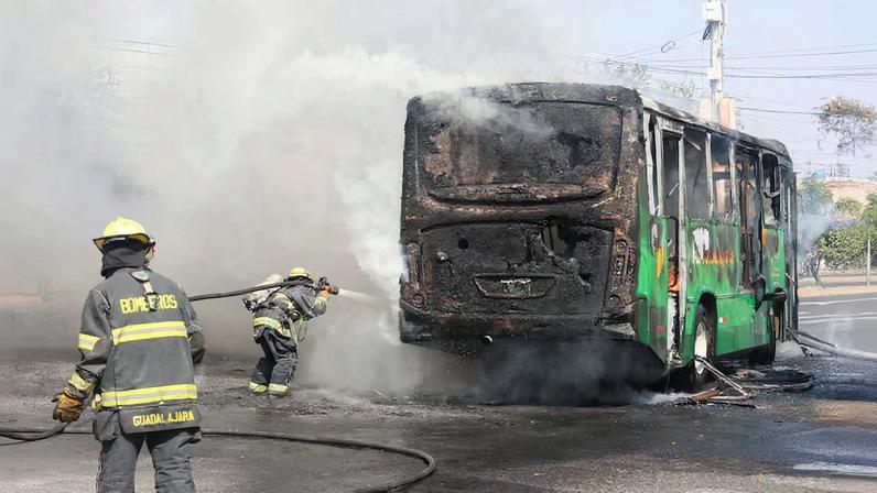 Firefighters work to extinguish flames from a vehicle used by organized crime members as roadblock following a series of detentions by federal forces, in Guadalajara, Mexico, February 22, 2026.