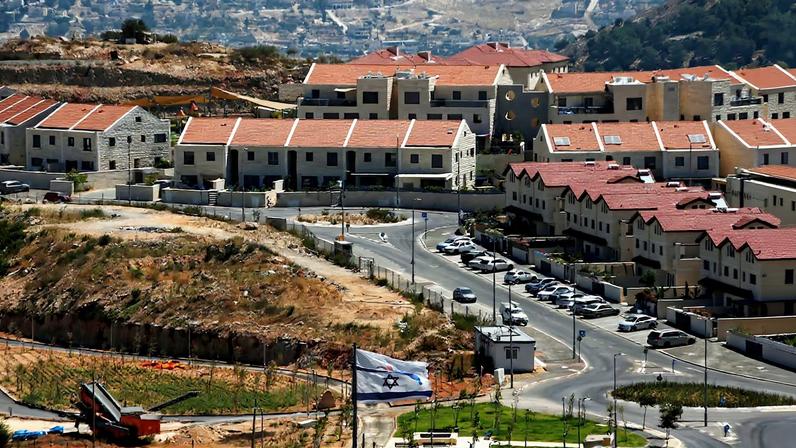 The Israeli national flag flutters as apartments are seen in the background in the Israeli settlement of Efrat in the Israeli-occupied West Bank