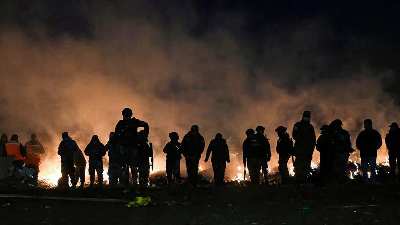 Members of the Bolivian military burn banknotes that fell from a Bolivian Air Force Hercules aircraft after it crashed on Friday evening onto a busy avenue amid inclement weather in the city of El Alto, Bolivia, February 28, 2026. REUTERS/Claudia Morales