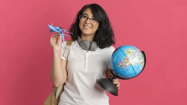 Aluna de intercâmbio segurando globo terrestre e avião de brinquedo.