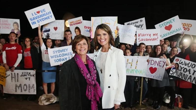 Savannah Guthrie and her mother Nancy Guthrie posing with fans holding "I Love Savannah in Sydney" signs at the Sydney Opera House.