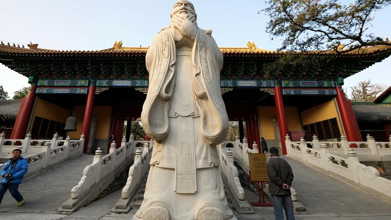 Visitors walk past a statue on the grounds of the Confucius Temple in Beijing on Nov. 22, 2008.