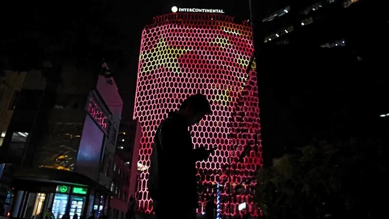 A man looks at his phone near a giant image of the Chinese flag on the side of a building in Beijing on Oct. 23, 2017.