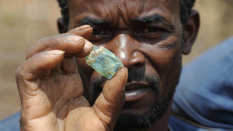 An artisanal miner holds up a fragment of copper-bearing ore at the Lukuzi.