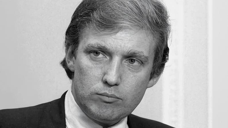 A black and white headshot of Donald Trump looking at a man in glasses at left.