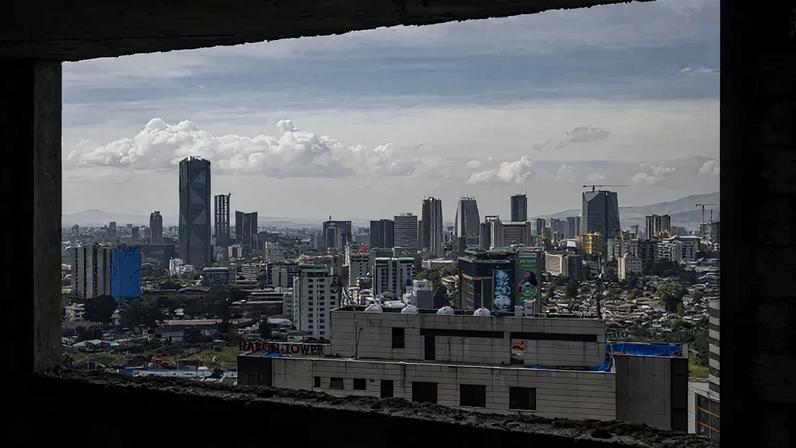 A skyline is shown from a window. There are skyscrapers, and it's a somewhat cloudy day.