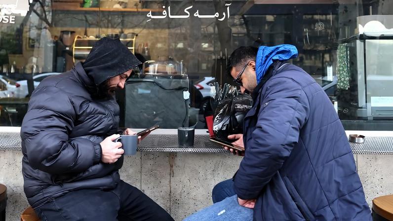 Men use their mobile phones while sitting at a coffee shop in north of Tehran on Jan. 7.