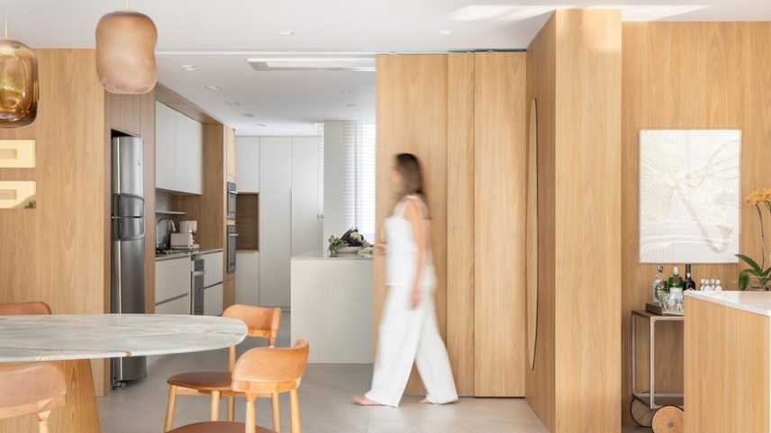 O piso de porcelanato, modelo Folk Ice, da Portobello, ressalta a unidade dos ambientes integrados. O painel de freijó, projetado pelo escritório e executado pela Evviva, serve para ocultar a ampla porta de correr que divide cozinha e área social