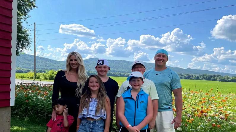 Kim Zolciak and Kroy Biermann with five children in a field of flowers.