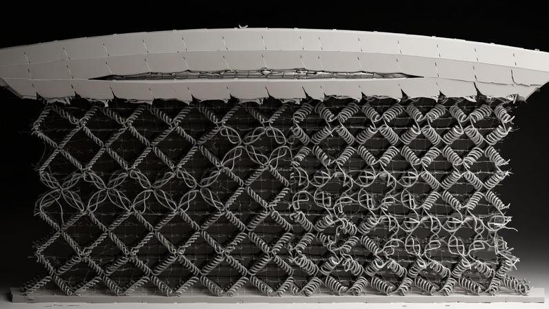 A black and white image of a woven metamaterial, comprised mostly of diamond-shaped cells woven from spiral fibers