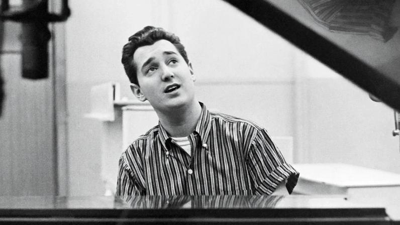 Singer Neil Sedaka seated at a piano, 1960.