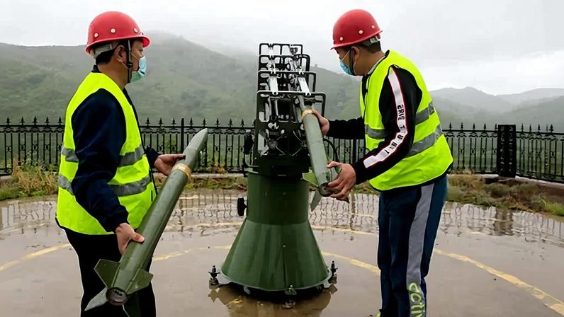 Getty Images Two men in yellow jackets and red helmets stand either side of a rocket launcher, with one loading a rocket. Mountains and mist can be seen in the background (Credit: Getty Images)