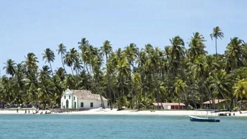 Capelinha, coqueiros e mar calmo fazem parte do cenário da Praia dos Carneiros (PE)