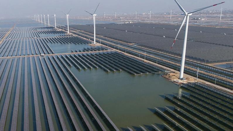 FILE - Wind turbines operate along a solar farm near Weifang in eastern China's Shandong province on March 22, 2024.