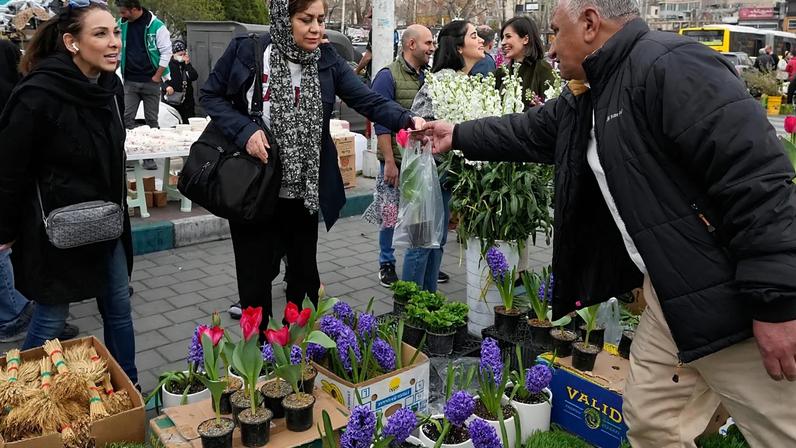 A woman shops flower ahead of the Persian New Year, or Nowruz, meaning "New Day," in northern Tehran