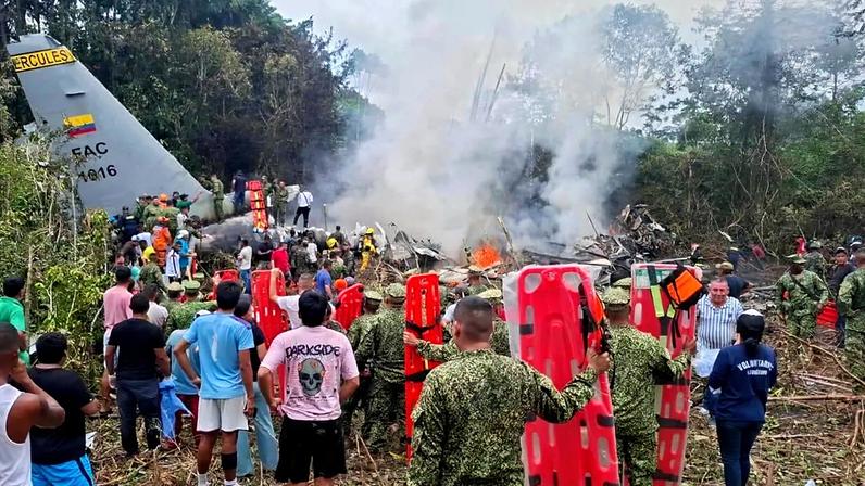People stand around a military cargo plane that crashed after taking off from Puerto Leguizamo, Colombia