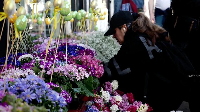 A woman looks at flowers on display outside an Iranian shop on Ballards Lane, in the Finchley area of London