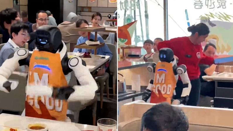 Robô com avental laranja escrito 'M FOOD' serve mesas em restaurante cheio de clientes. Pessoas estão sentadas e interagindo ao fundo, enquanto o robô se move entre as mesas.