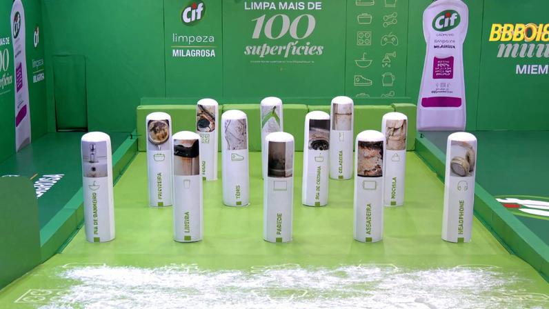 Pista de boliche verde com pinos brancos decorados com imagens de superfícies sujas. Fundo verde exibe texto promocional da marca CIF destacando limpeza em mais de 100 superfícies. Ambiente interno com iluminação uniforme.
