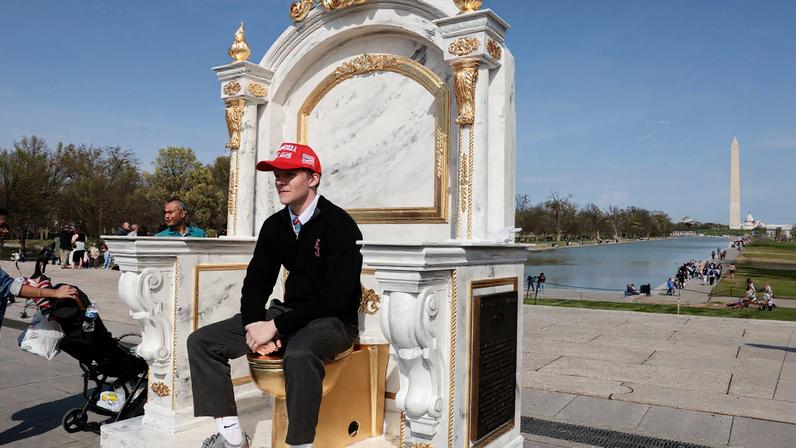 Homem sentado no vaso sanitário dourado instalado por artistas em Washington