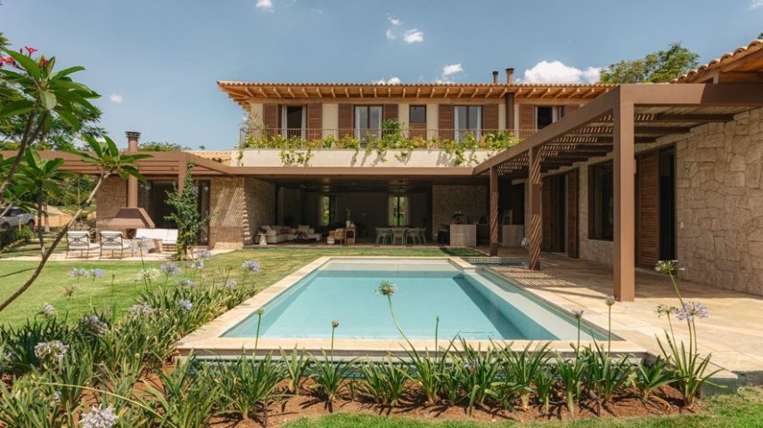 PISCINA | Os interiores se conectam com a área externa, onde estão piscina e varandas com pergolados metálicos pintados de marrom, cor Beijo Baiano, da Suvinil. Ao redor da piscina, agapanto e jasmim-rosa; ao fundo, subindo o pergolado, primavera vermelha; e no guarda-corpo do terraço superior, alamanda amarela. Paisagismo assinado por Bia Abreu