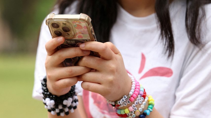 Jovem usa o celular em Sidney, na Austrália; país aprovou lei que proíbe acesso de menores de 16 anos às redes sociais — Foto: Hollie Adams/Reuters
