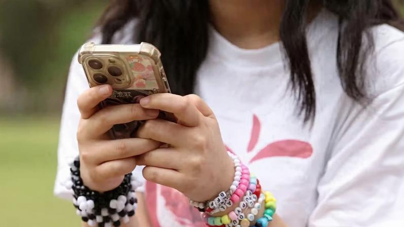 Jovem usa o celular em Sidney, na Austrália; país aprovou lei que proíbe acesso de menores de 16 anos às redes sociais — Foto: Hollie Adams/Reuters