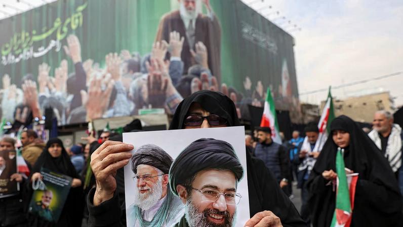 A woman holds an image of Iran's new supreme leader, Mojtaba Khamenei, alongside late Iranian Supreme Leader Ayatollah Ali Khamenei, during a funeral ceremony for the Iranian military commanders who were killed in strikes, amid the U.S.-Israeli conflict with Iran, in Tehran, Iran, March 11, 2026. Majid Asgaripour/WANA (West Asia News Agency) via REUTERS