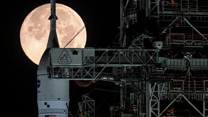 Fotografia da Lua cheia é vista atrás do foguete Artemis II SLS (Space Launch System) da NASA e da espaçonave Orion, posicionados sobre uma plataforma de lançamento móvel no Complexo de Lançamento 39B, no domingo, 1º de fevereiro de 2026, no Centro Espacial Kennedy, na Flórida.