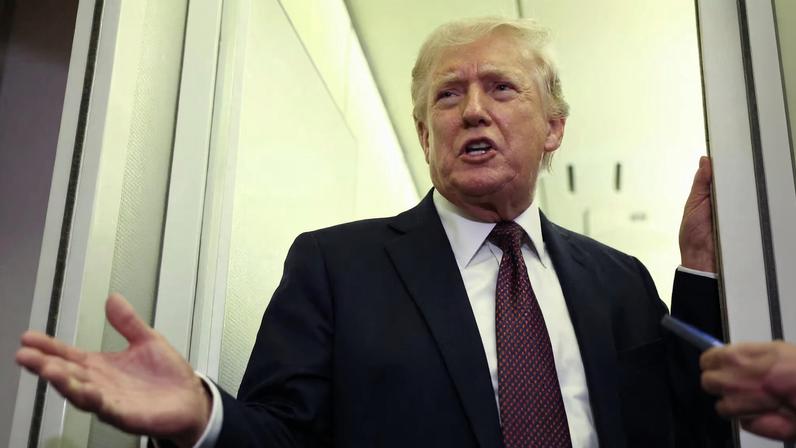 U.S. President Donald Trump speaks to reporters aboard Air Force One