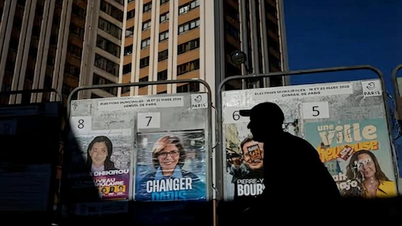 Un hombre pasa por delante de algunos carteles de propaganda electoral en París.