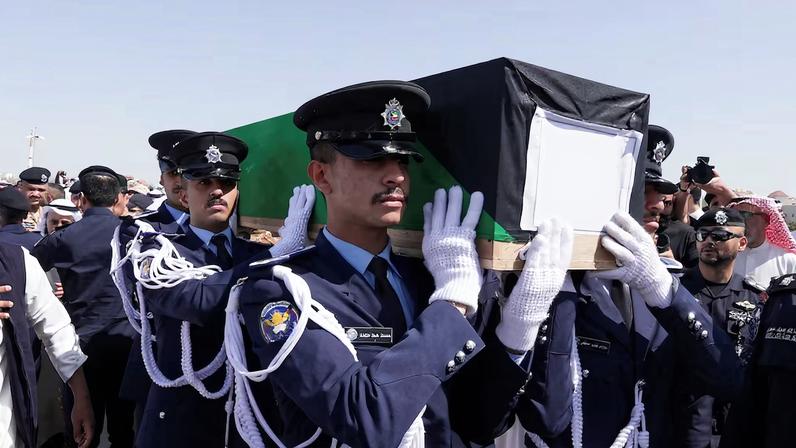 Guards of Honour carry the coffin of one of two police officers, who were killed while performing their duties, during their funeral procession at a graveyard in Kuwait City