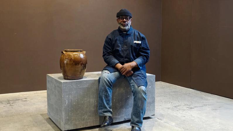 Theaster Gates inside the exhibition, Dave: All My Relations at Gagosian's 821 Park Avenue location in New York, with the historic work by David Drake from his personal collection that he is gifting to Dave's descendants, and seated on a new sculpture he made by pulverizing around 45 of his own pots Photo: Maris Hutchinson