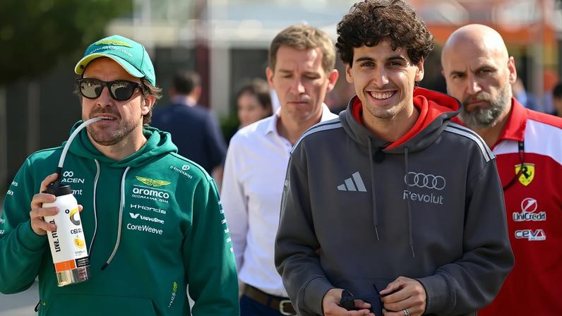 O espanhol da Aston Martin Fernando Alonso e o brasileiro da Audi Gabriel Bortoleto caminham pelo paddock no primeiro dia do segundo teste de pré-temporada da Fórmula 1 no Circuito Internacional do Bahrein, em Sakhir, em 18 de fevereiro de 2026 (Foto: Giuseppe cacace/afp)