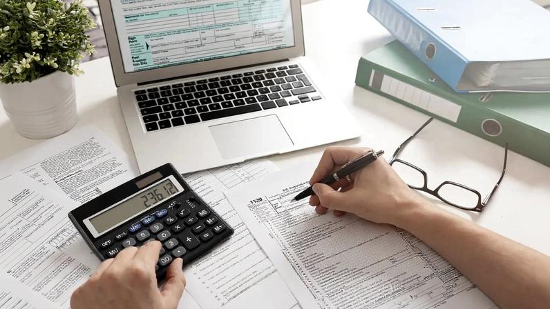 Imagem de uma mesa com papéis, notebook, calculadora etc para ilustrar guia Imposto de Renda 2026: como declarar? Confira guia completo