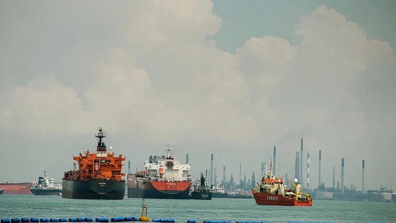 Uma tomada ampla de várias grandes embarcações comerciais, incluindo petroleiros e um barco de pesquisa, flutuando no mar.