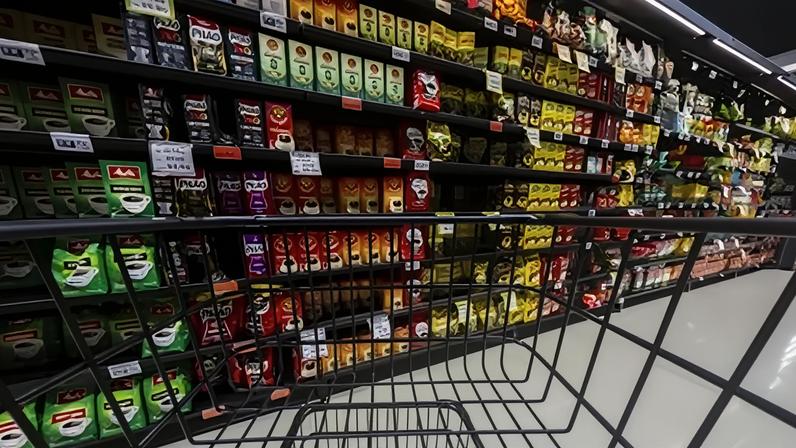 Carrinho vazio parado na frente das prateleiras com diferentes marcas de café e preços diversos no interior de um supermercado na cidade de Marília, no interior de São Paulo
