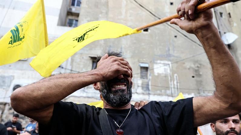 A man reacts while holding a Hezbollah flag during the funeral of people killed after hundreds of paging devices exploded in a deadly wave across Lebanon the previous day, in a south Beirut district, on September 18, 2024.