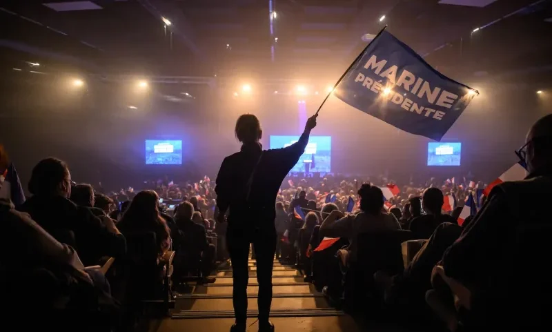 An attendee wave a flag prior to a rally of the French far-right Rassemblement National (RN) party candidate in Perpignan ahead of France's municipal elections in Perpignan, southern France, on February 28, 2026.