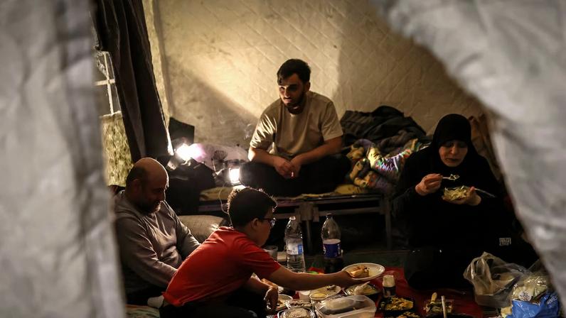 Salam Issa Rida, 43, her husband Ahmed Rida, 43, and other family members break their fast at iftar during Ramadan as they shelter at Camille Chamoun Stadium, following an escalation between Hezbollah and Israel amid the U.S.-Israeli conflict with Iran, in Beirut, Lebanon, March 14, 2026. REUTERS/Claudia Greco