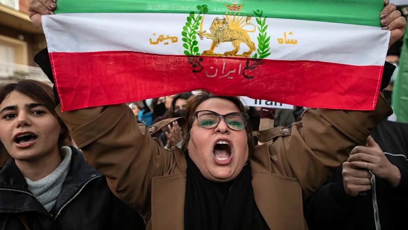 A woman shouting and waving the Iranian Lion and Sun flag (formerly used during the late Qajar and Pahlavi eras) during a protest outside the Embassy of Iran on Jan. 14, 2026